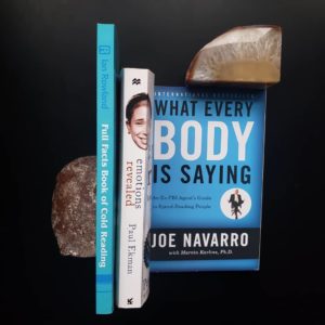 Three books about body language barrier on a black table with two decorative stones