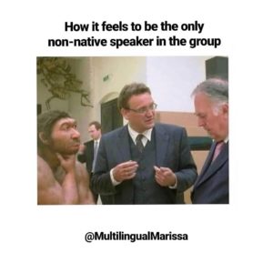 A meme showing a caveman with two business men that reads "How it feels to be the only non-native speaker in the group"