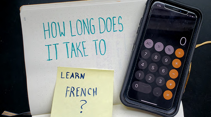 The words "how long does it take to learn French" written on paper in marker with a calculator