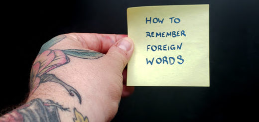 A hand holding a sticky note that says "how to remember foreign words"