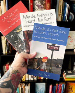 An image of the Merde trilogy French books being held together